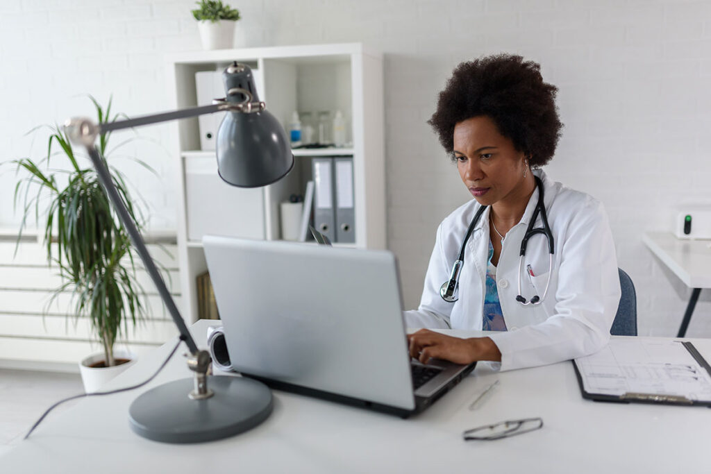 Doctor performing topic research on a laptop.