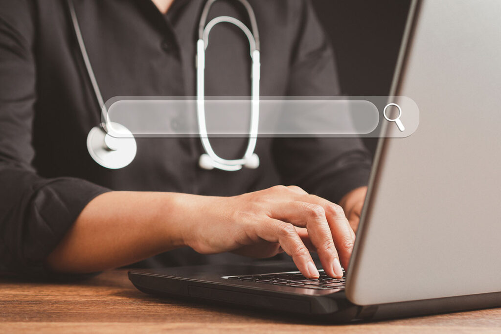 A doctor typing on a computer in relation to medical keyword research.