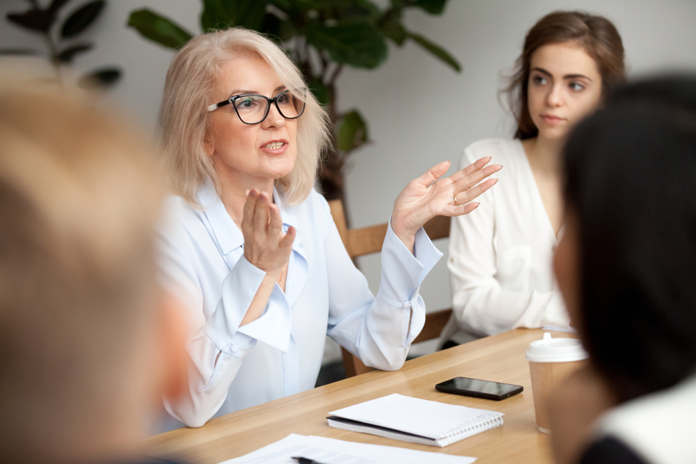 A senior professional conducting a focus group with attentive participants.