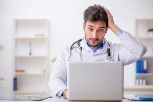 Doctor with a laptop realizing a mistake in his marketing efforts.